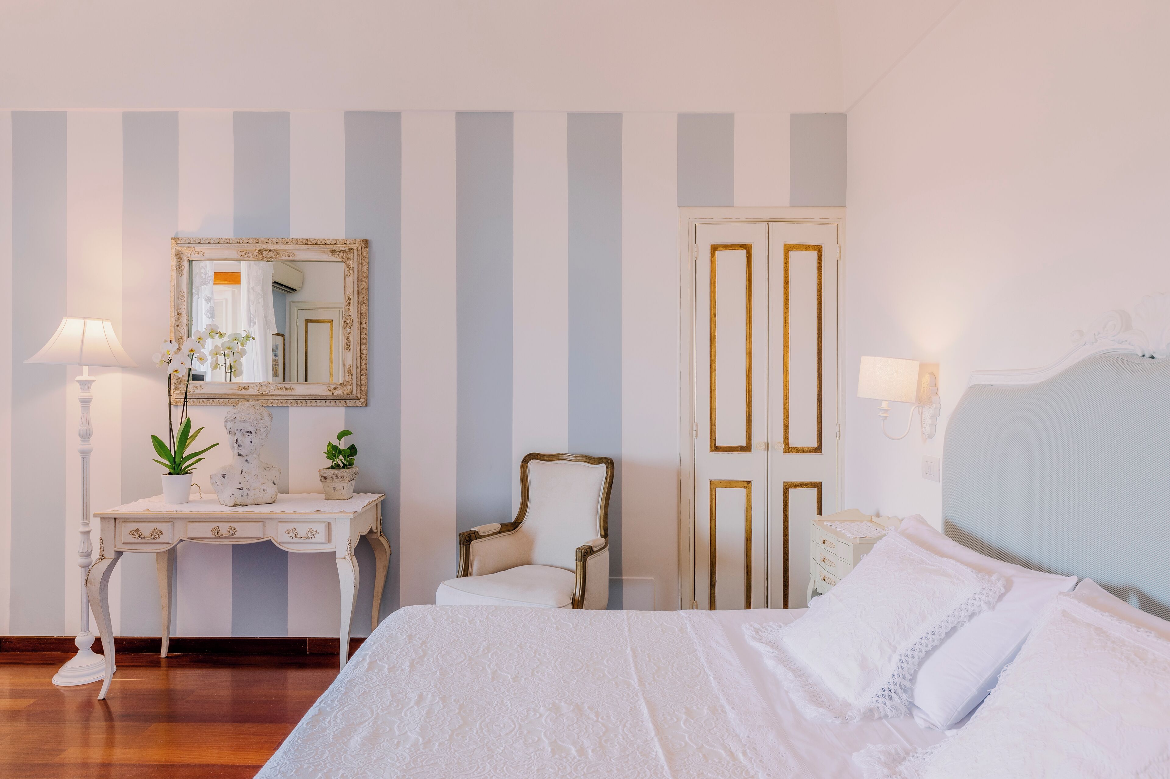 A bedroom with a bed, a dresser, a chair, a mirror, and a door.
