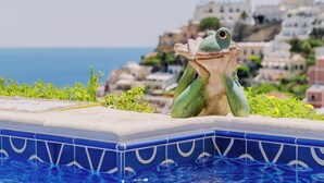 A frog statue on a poolside with a view of coastal buildings. - Villa Mary Suites (Positano)