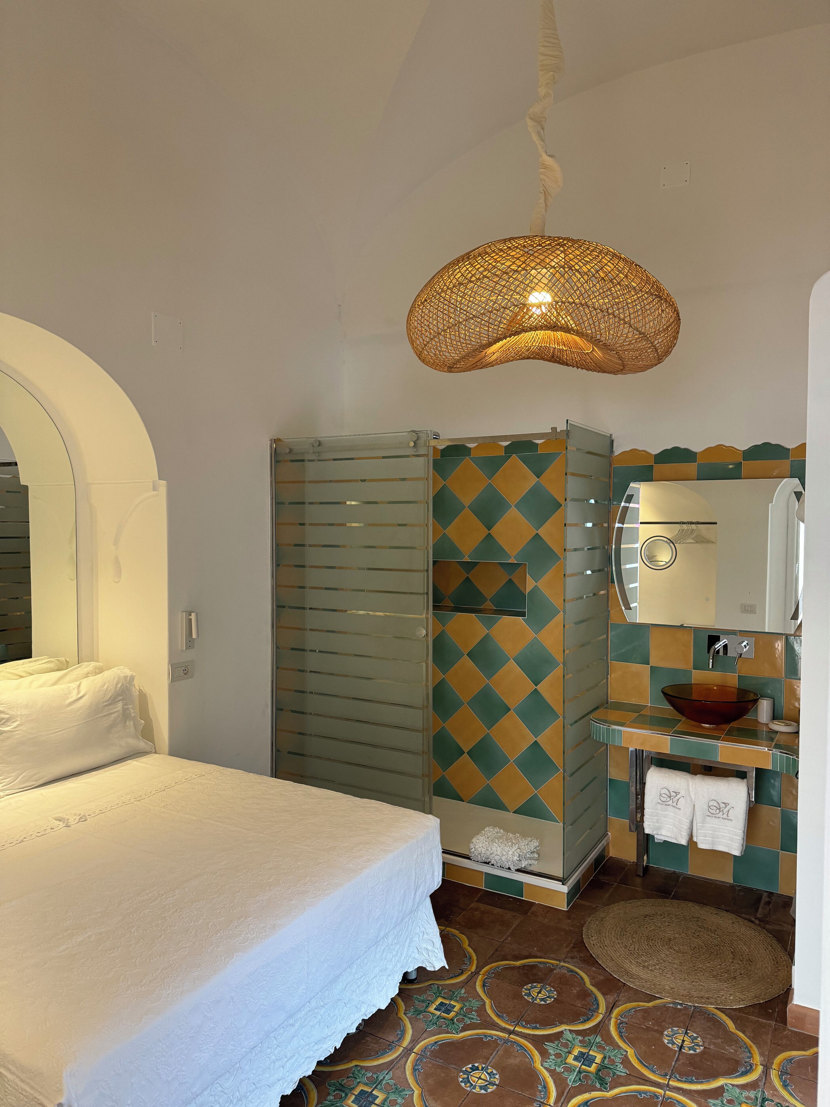 Ein Hotelzimmer mit einem Bett, einer Dusche, einem Waschbecken und einem Spiegel.