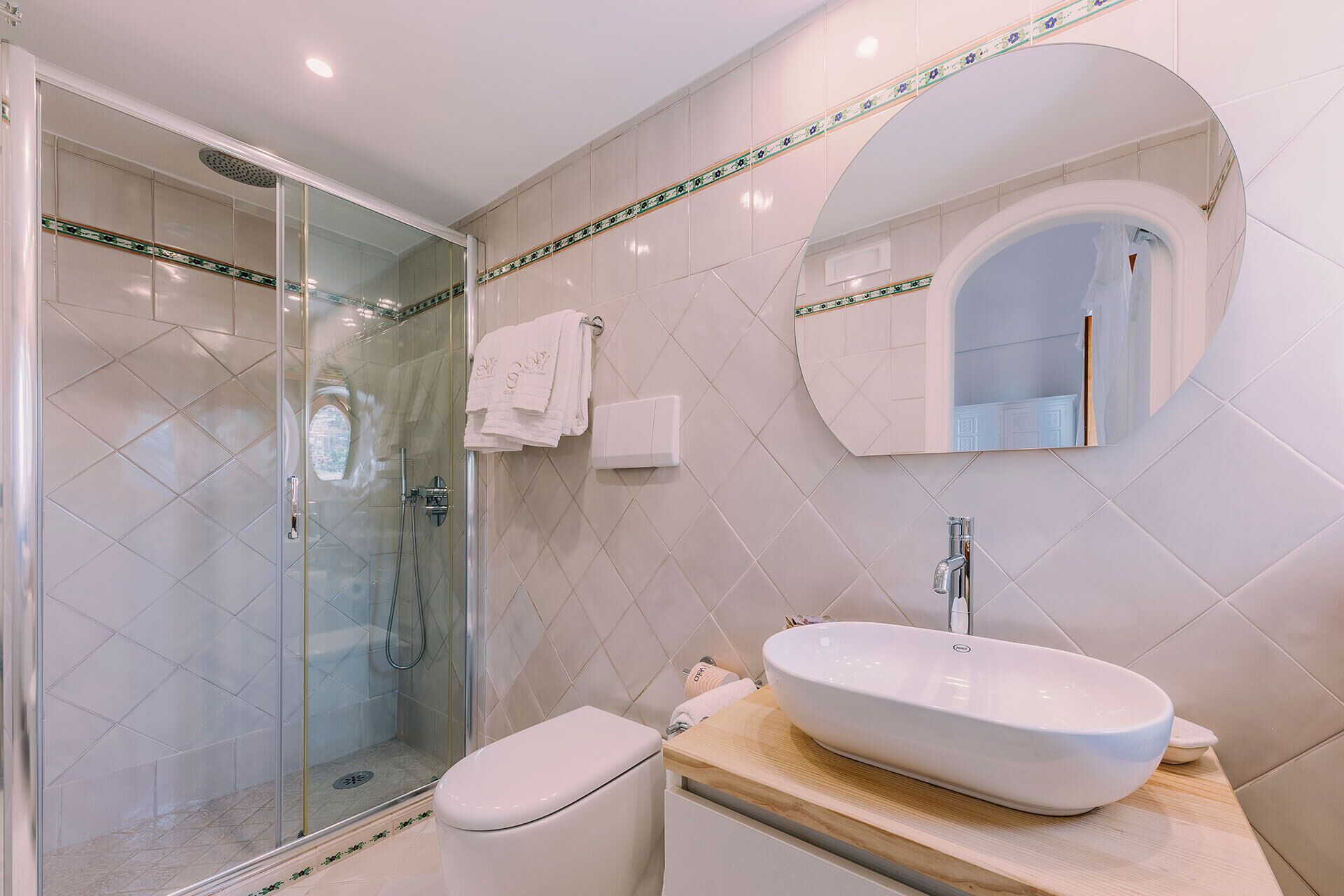 A modern bathroom with a glass-enclosed shower, a white sink, and a vanity with a mirror.
