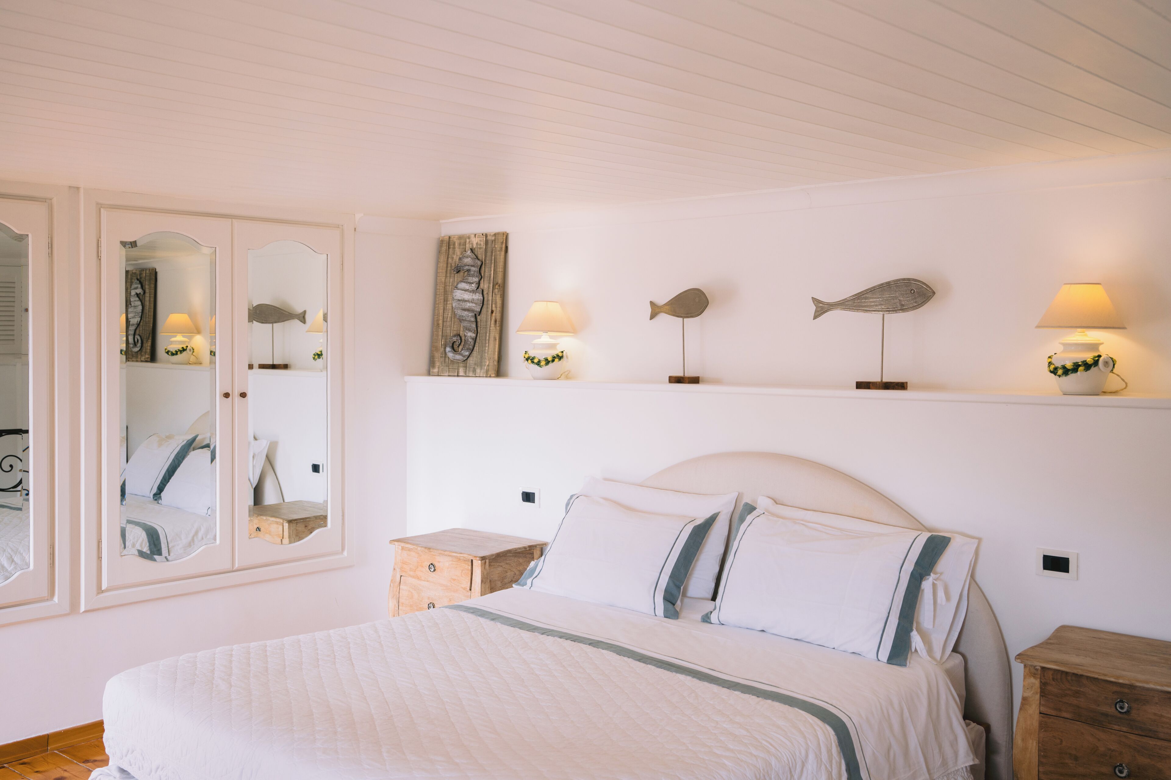 Une chambre à coucher comprenant un lit, des tables de chevet, un miroir et des lampes fixées au mur.