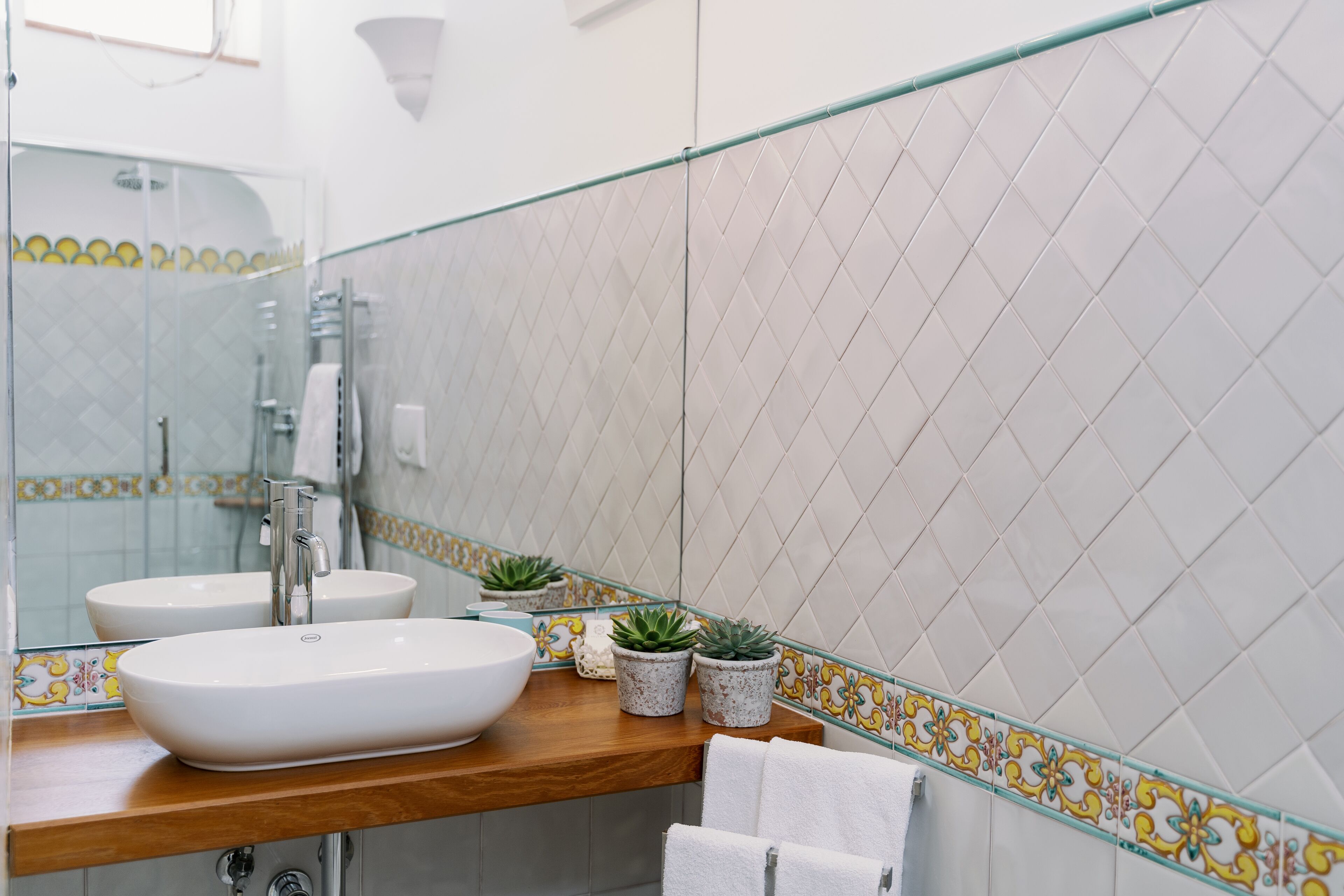 A bathroom with two sinks, a glass shower enclosure, and decorative tiles.