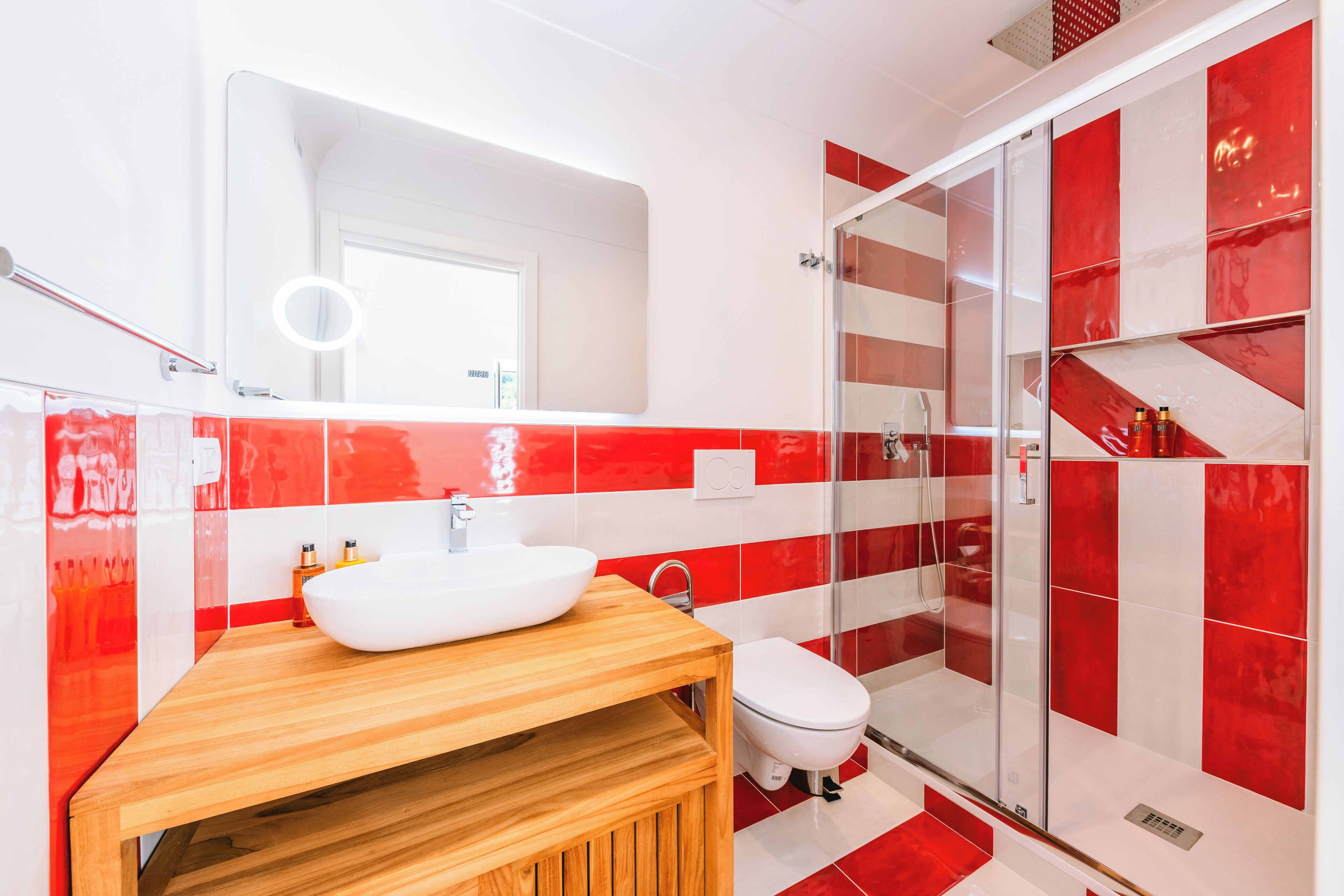 A modern bathroom with a white sink, wooden vanity, and a glass shower enclosure.