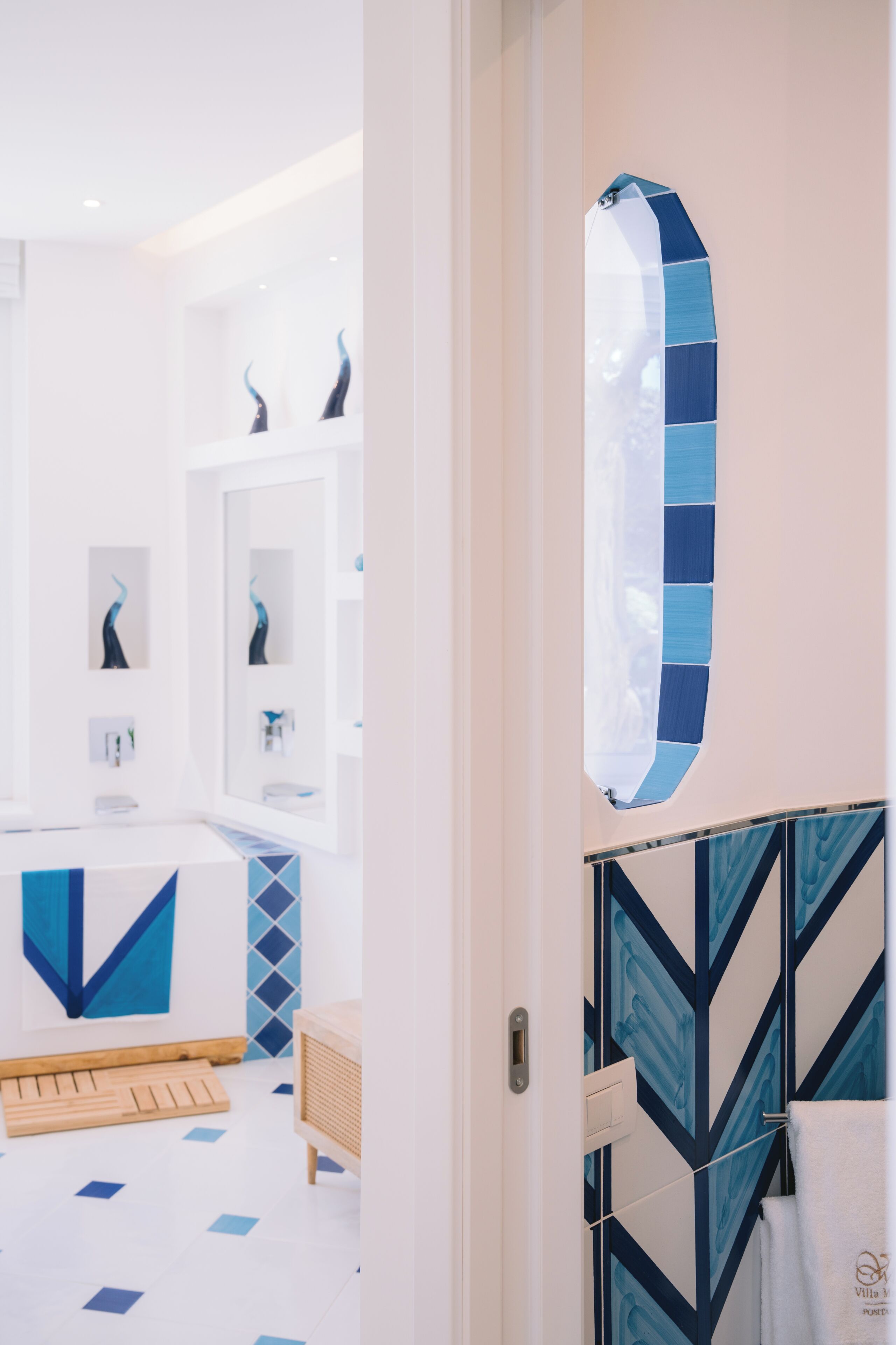 A modern bathroom with a white sink, mirror, and geometric patterned tiles.