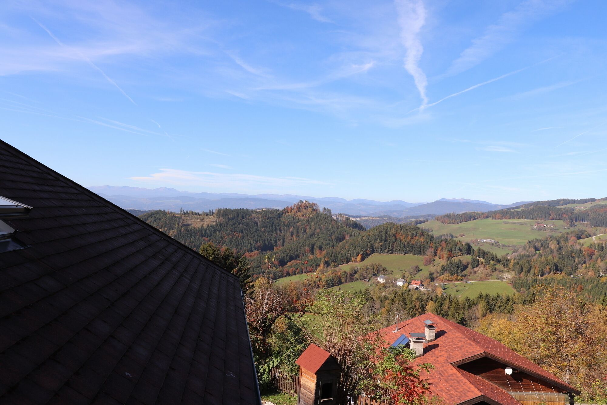 Aussicht auf eine Berglandschaft mit einem Haus im Vordergrund und einem klaren Himmel.