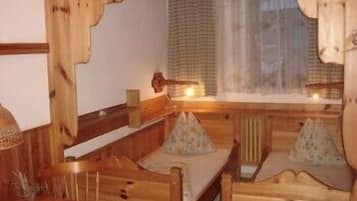 Een gezellig houten kamer met een bed, een klein tafeltje en een raam met gordijnen.