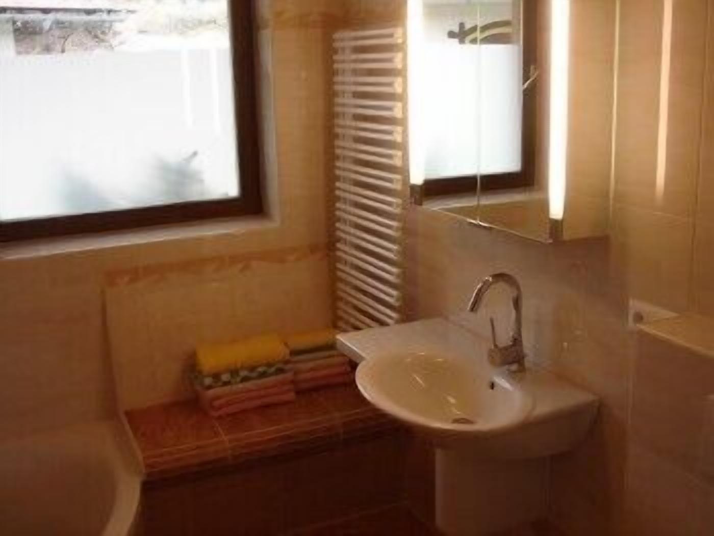 Une salle de bain équipée d’un lavabo, d’un miroir, d’une fenêtre et d’un porte-serviettes.