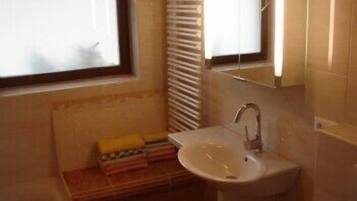 Une salle de bain équipée d’un lavabo, d’un miroir, d’une fenêtre et d’un porte-serviettes.