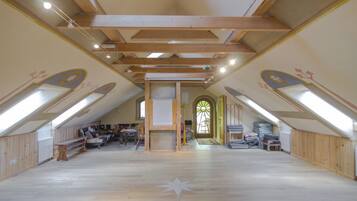 An attic room with wooden beams, a star-shaped floor design, and a large window with a stained glass design.