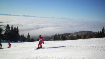 A snowy mountain landscape with a snowboarder in the foreground and a skier in the background.