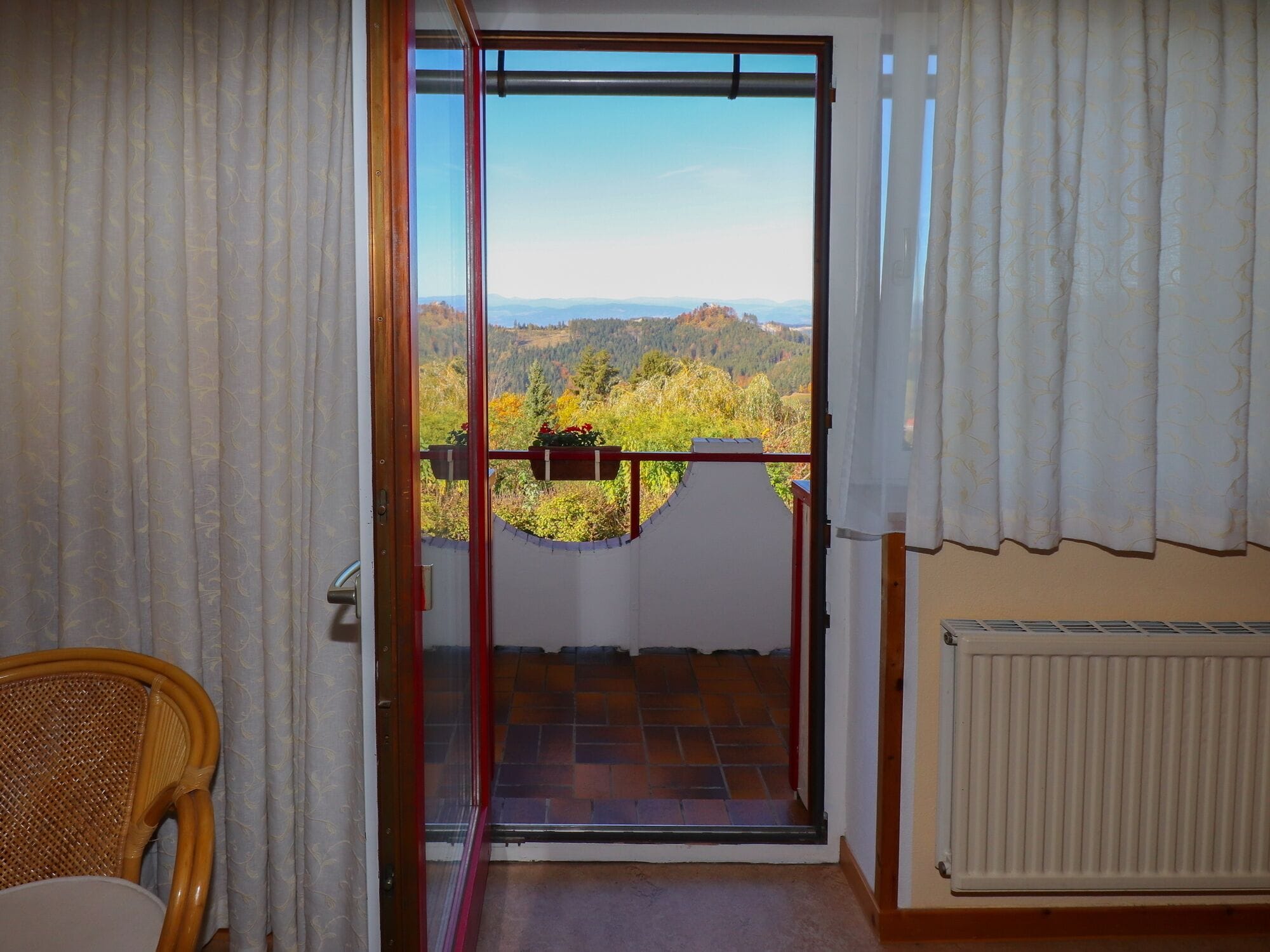 A room with a view of a mountainous landscape through a glass door.