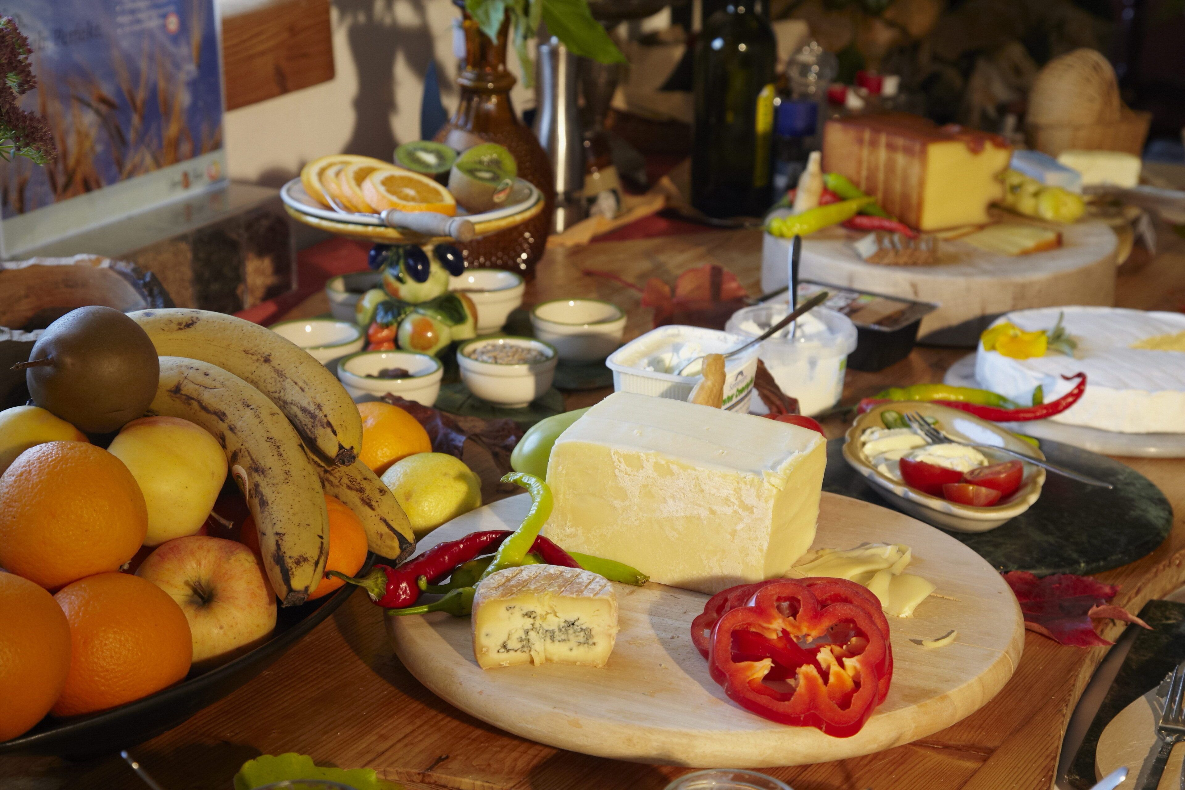 A table with various fruits, cheese, and condiments.