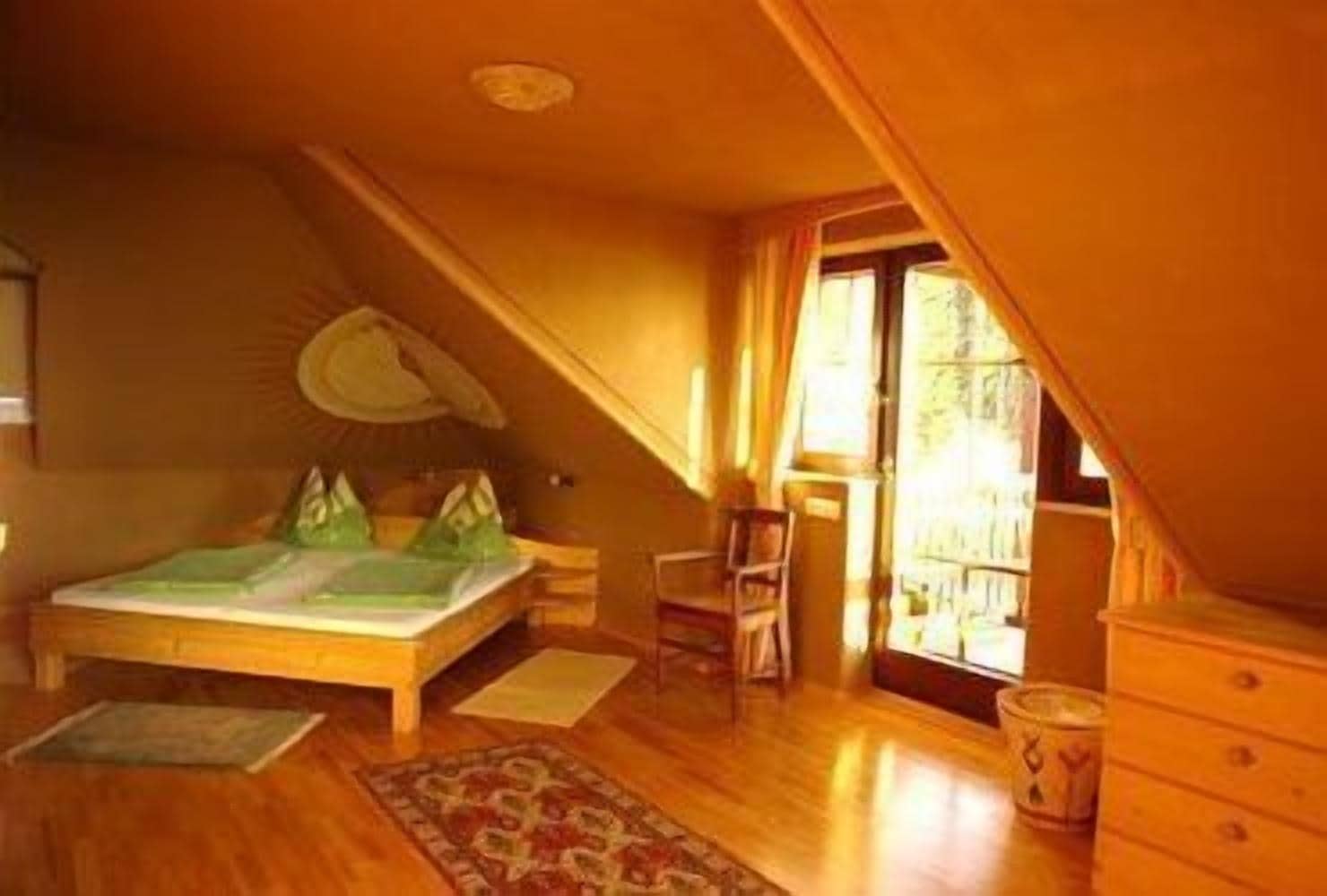 A bedroom with a bed, a chair, a dresser, and a window.