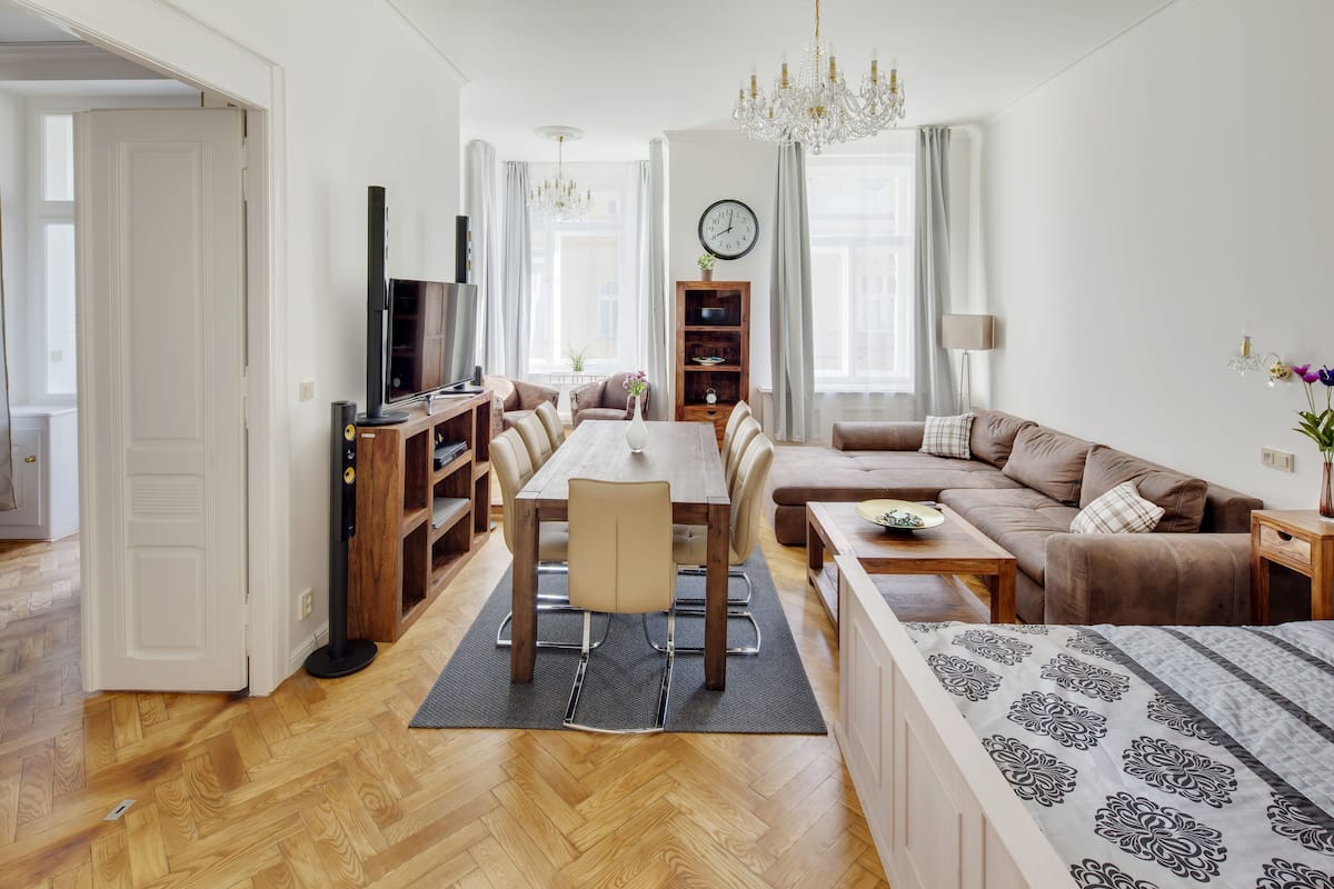 A modern living room with a wooden dining table, sofa, and a TV.