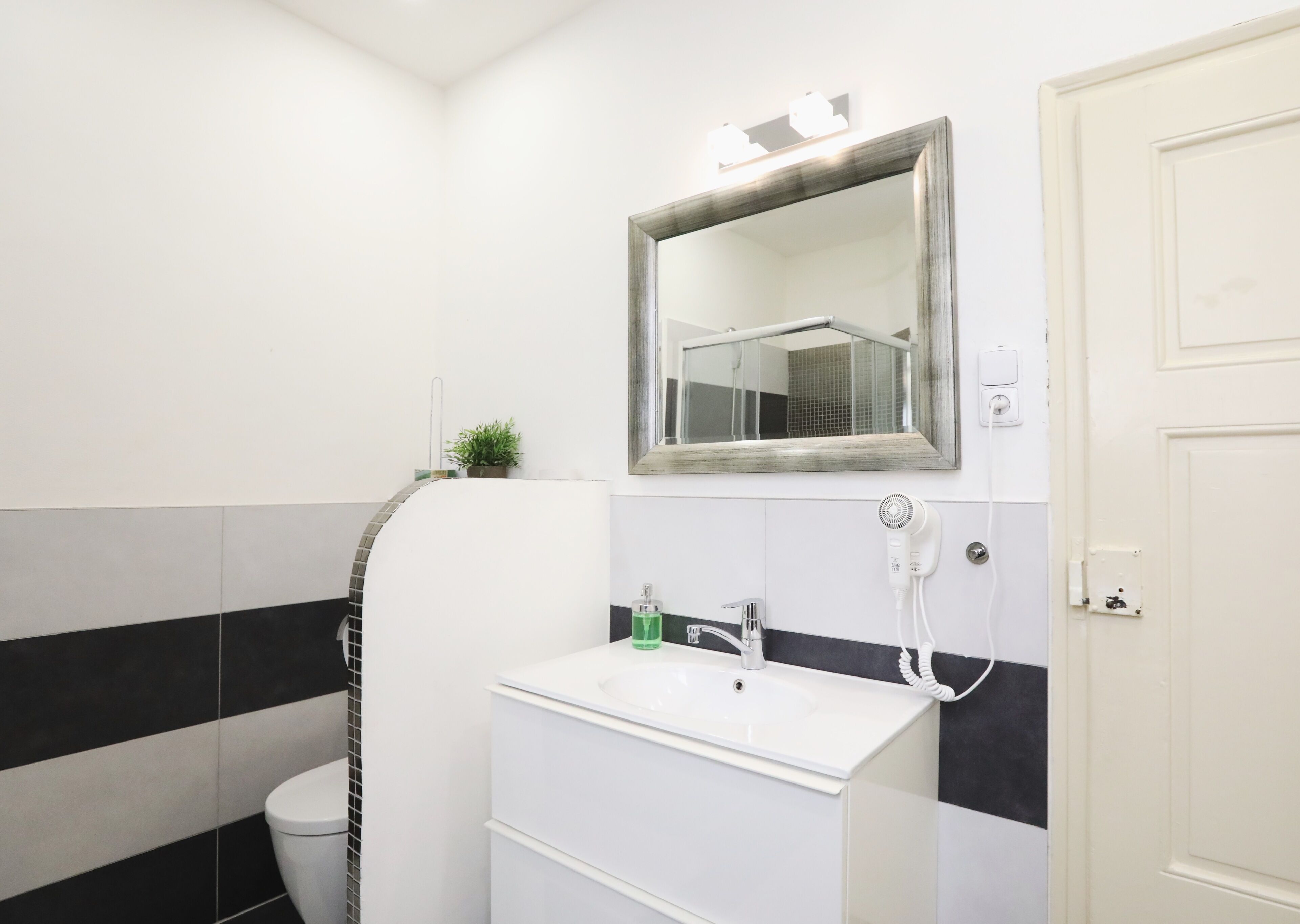 A bathroom with a white sink, a mirror, a towel rack, and a toilet.
