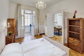 Un dormitorio con una cama grande, un armario de madera y vista al área de estar por una puerta abierta.
