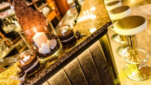 Zona de bar con un postre de chocolate, velas y taburetes.