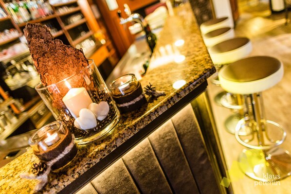 A bar area with a chocolate dessert, candles, and bar stools. - Hotel Touring (Santa Cristina Val Gardena)