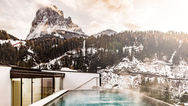 Un hotel moderno con piscina que domina un paisaje montañoso nevado.