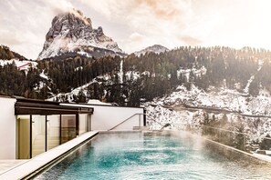 Ein modernes Hotel mit Pool und Blick auf eine verschneite Berglandschaft.