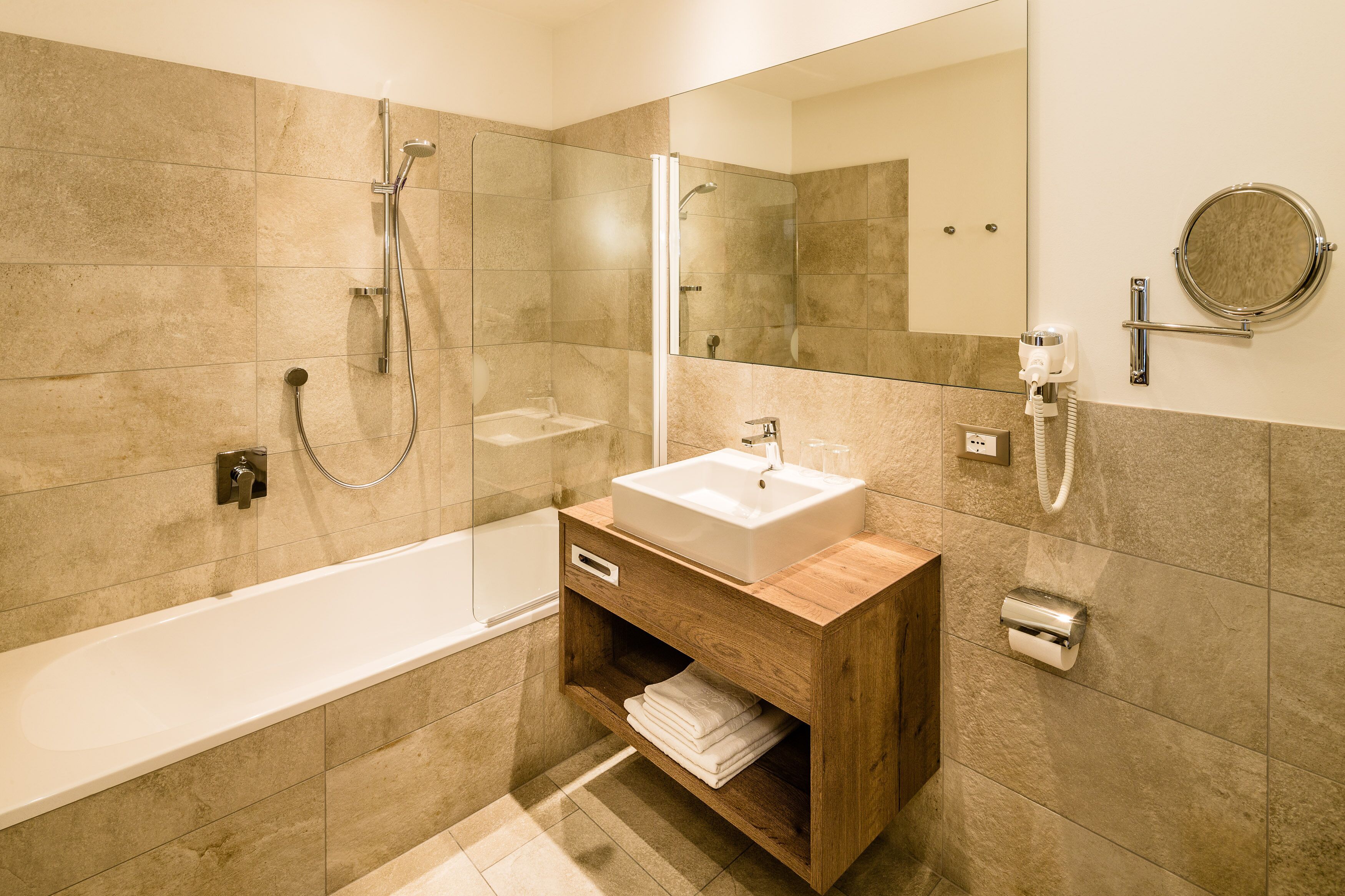 A modern bathroom with a bathtub, a vanity with a sink, a mirror, and a shower area.