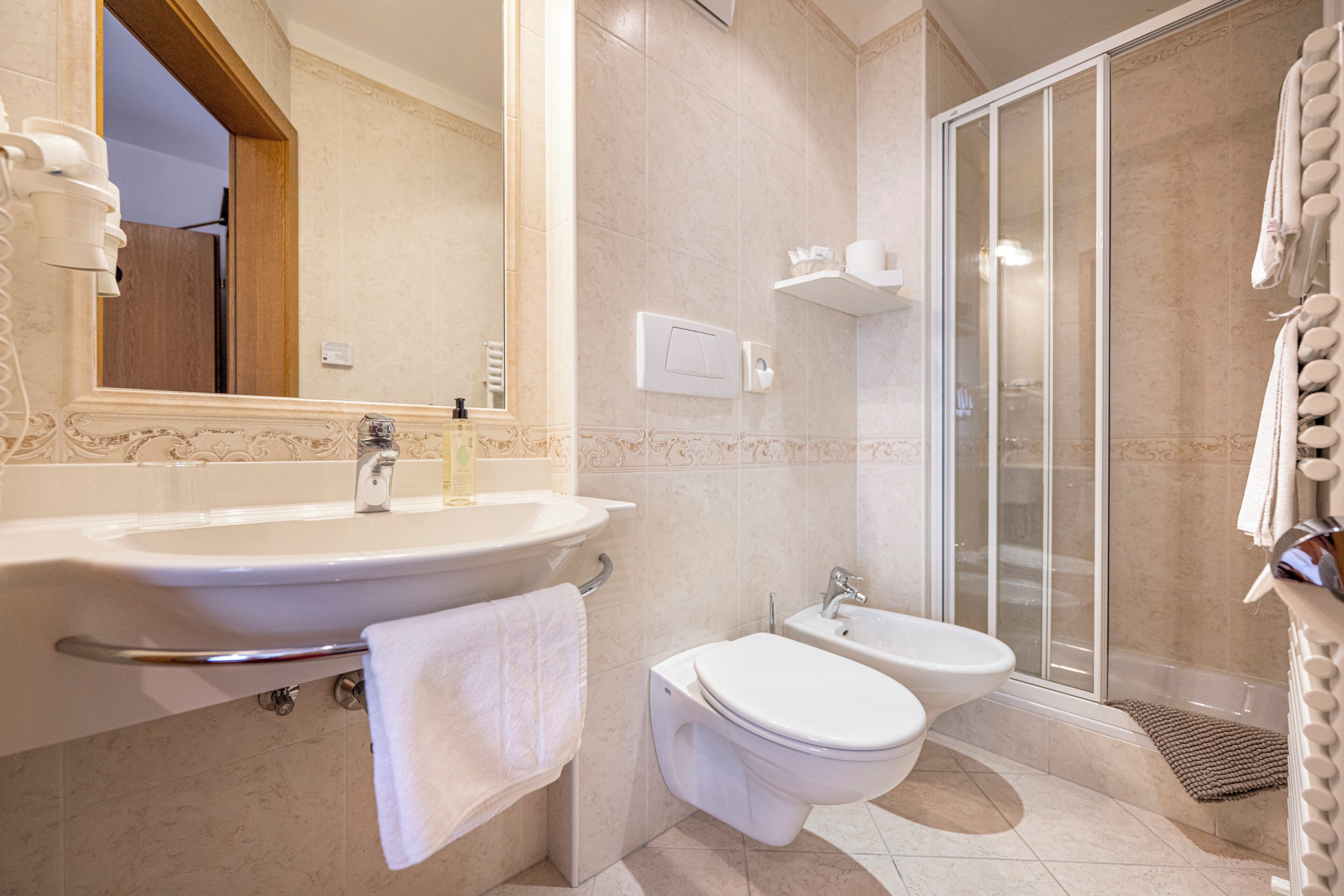 Een moderne badkamer met een wastafel, toilet, douchecabine en bidet.