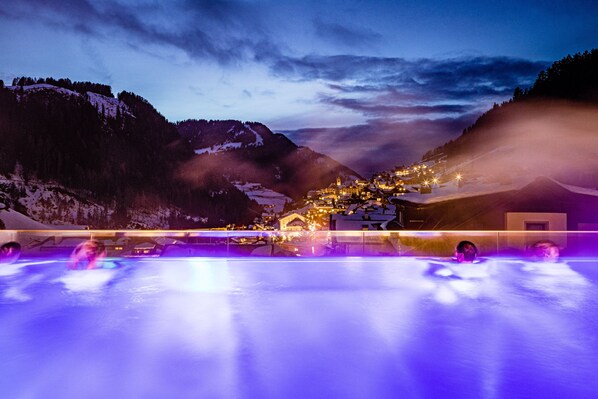 A snow-covered mountain landscape with a lit-up village and a frozen lake in the foreground. - Hotel Touring (Santa Cristina Val Gardena)