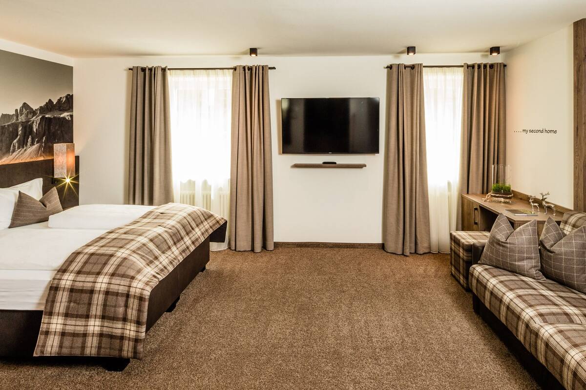 Une chambre d’hôtel avec un lit, un canapé, une télévision et un tableau au mur.