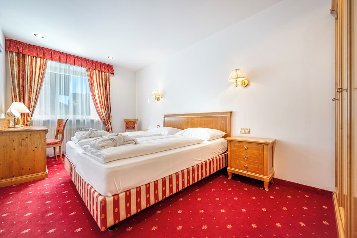 Une chambre d’hôtel avec un grand lit, une table de chevet en bois, un bureau avec une lampe et une chaise.