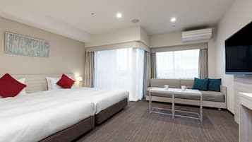 Una habitación de hotel con una cama grande, un sofá, una mesita y un televisor.