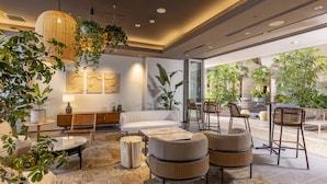 A modern living room with a sofa, two armchairs, a coffee table, and a side table. There are potted plants, a lamp, and artwork on the wall. - Tokyu Stay Yotsuya Shinjuku Area (Tokyo)