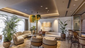 A modern living room with a sofa, armchairs, a coffee table, and a dining area with chairs. There are potted plants and artwork on the walls. - Tokyu Stay Yotsuya Shinjuku Area (Tokyo)