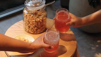 Una mesa de madera con un tarro de vidrio lleno de nueces, dos vasos de una bebida rosada y un tazón de nueces.