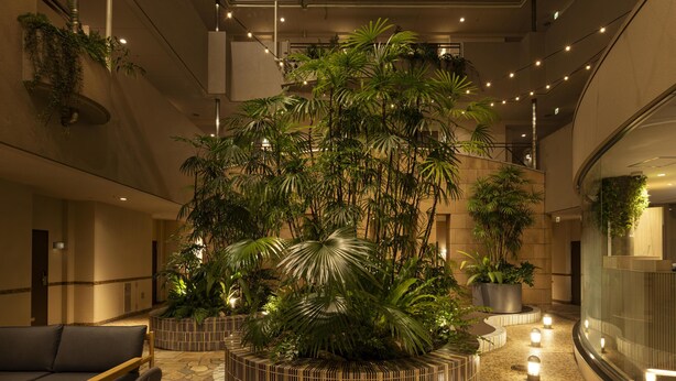 A lobby with a central planter, seating area, and a curved reception desk. - Tokyu Stay Yotsuya Shinjuku Area (Tokyo)