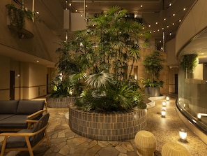 A lobby with a central planter, seating area, and a curved reception desk. - Tokyu Stay Yotsuya Shinjuku Area (Tokyo)