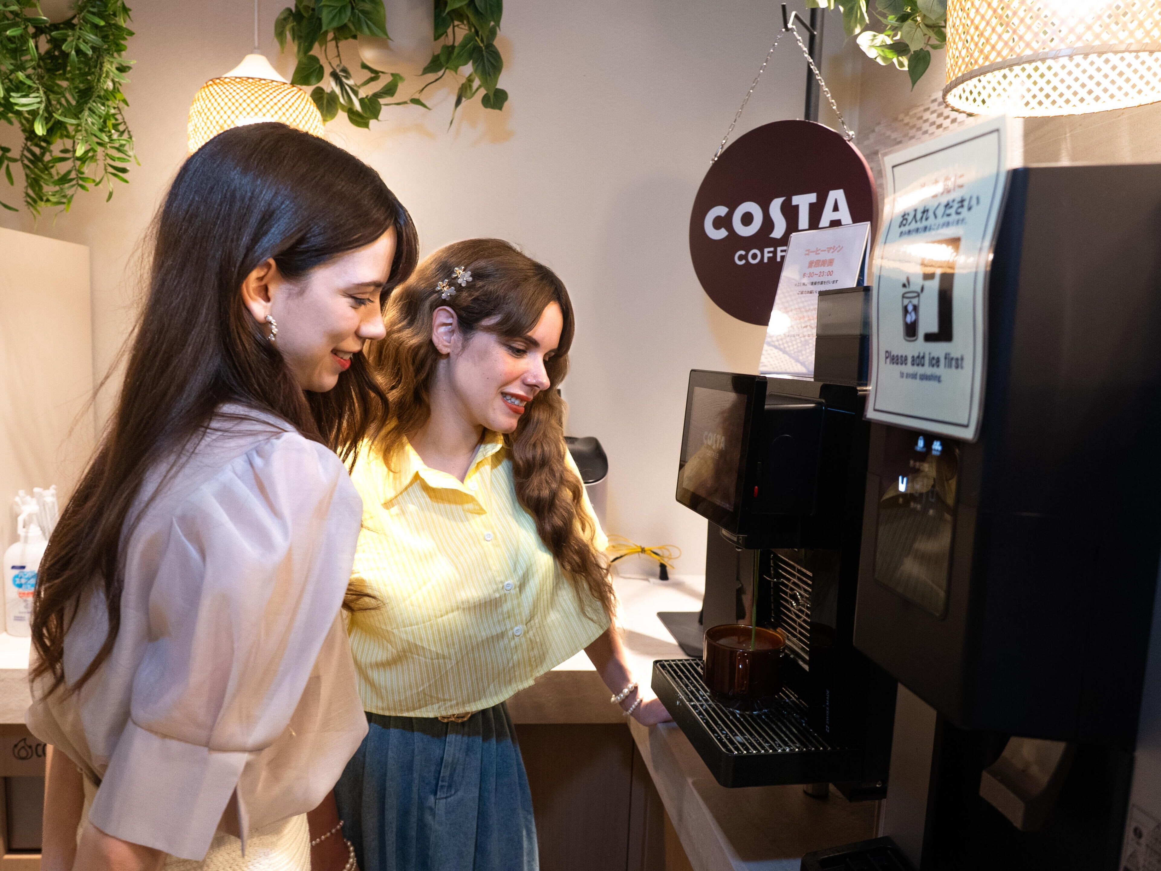 Dos personas usando una máquina de café en Costa Coffee.
