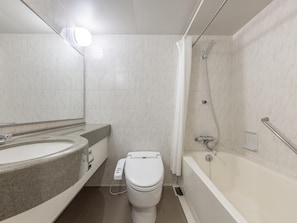 Features a large sink, separate toilet area, and a shower with handheld showerhead and glass-enclosed tub.