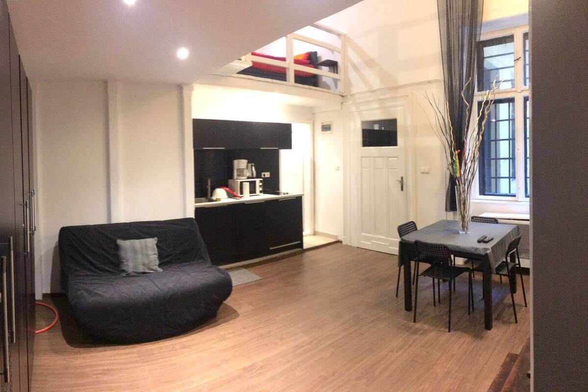 Un espacio habitable compacto con sofá, una mesa de comedor con sillas, kitchenette y ventana con vistas.