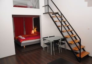 Una habitación pequeña con cama, una mesa y una escalera.