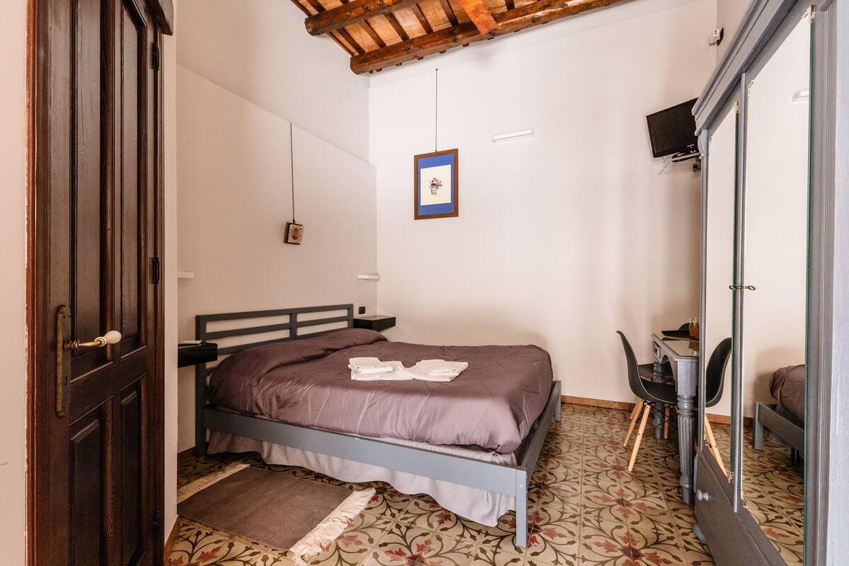 A bedroom with a bed, a desk, a chair, and a wardrobe.