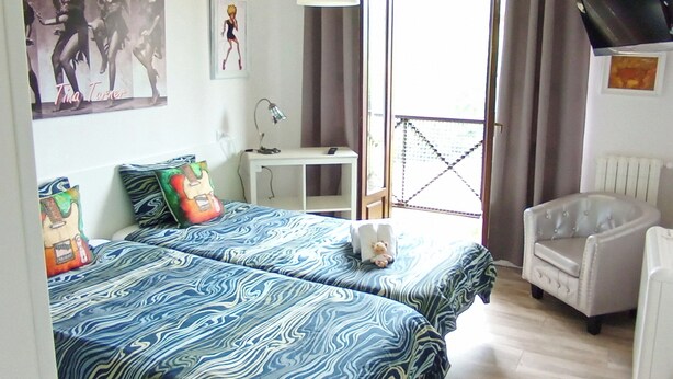 A bedroom with two beds, a desk, a chair, and a TV mounted on the wall. - Prau Riu (Llanes)