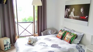 A bedroom with a bed, pillows, a nightstand, a lamp, and a window with curtains. - Prau Riu (Llanes)