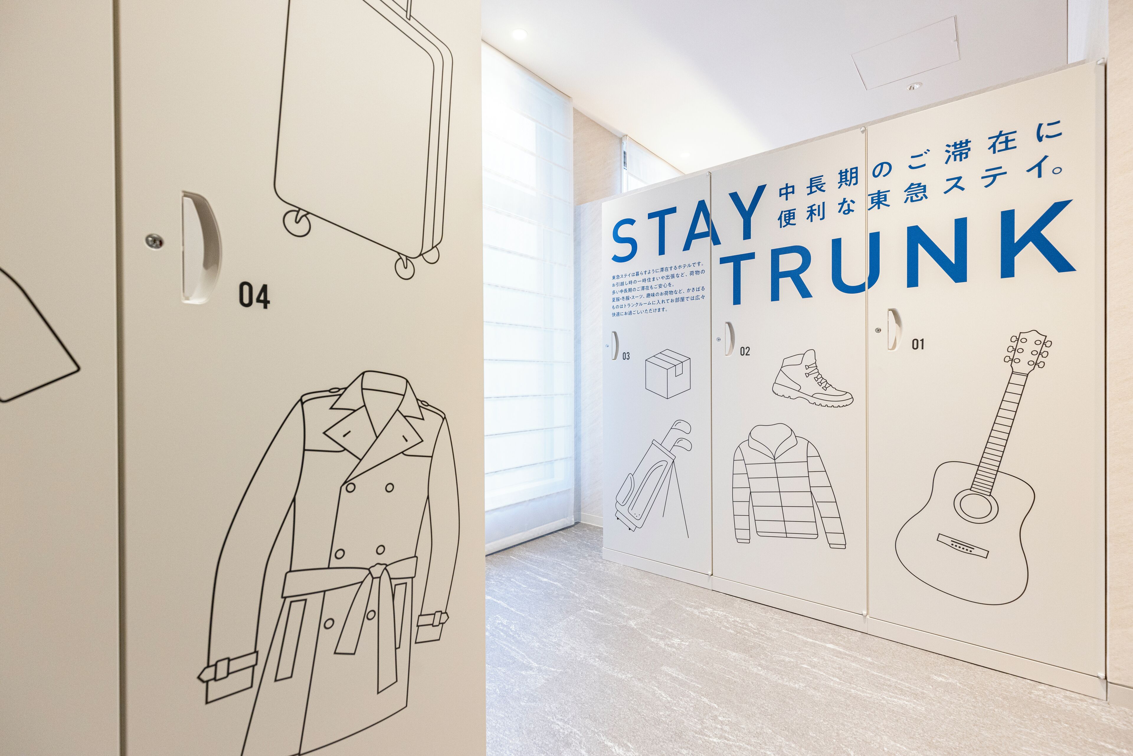 Quarto de hotel com uma parede grande com ilustrações de malas e o texto "STAY TRUNK".