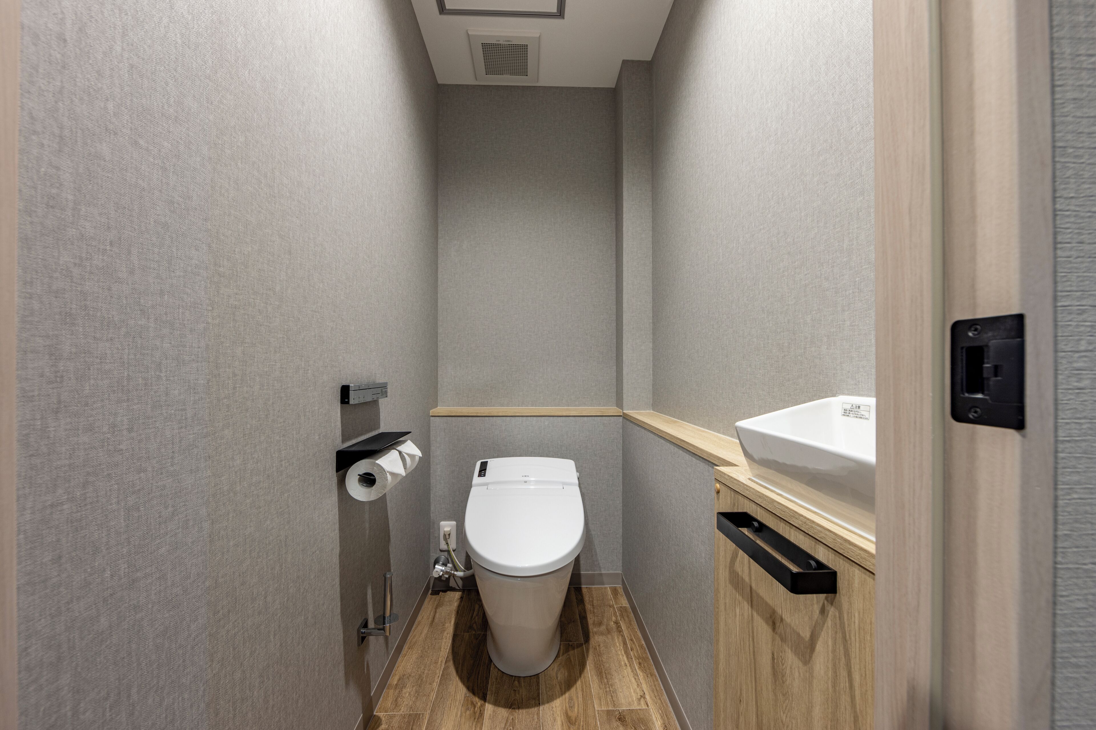 Une petite salle de bain moderne équipée de toilettes, d’un lavabo et d’un distributeur de serviettes.