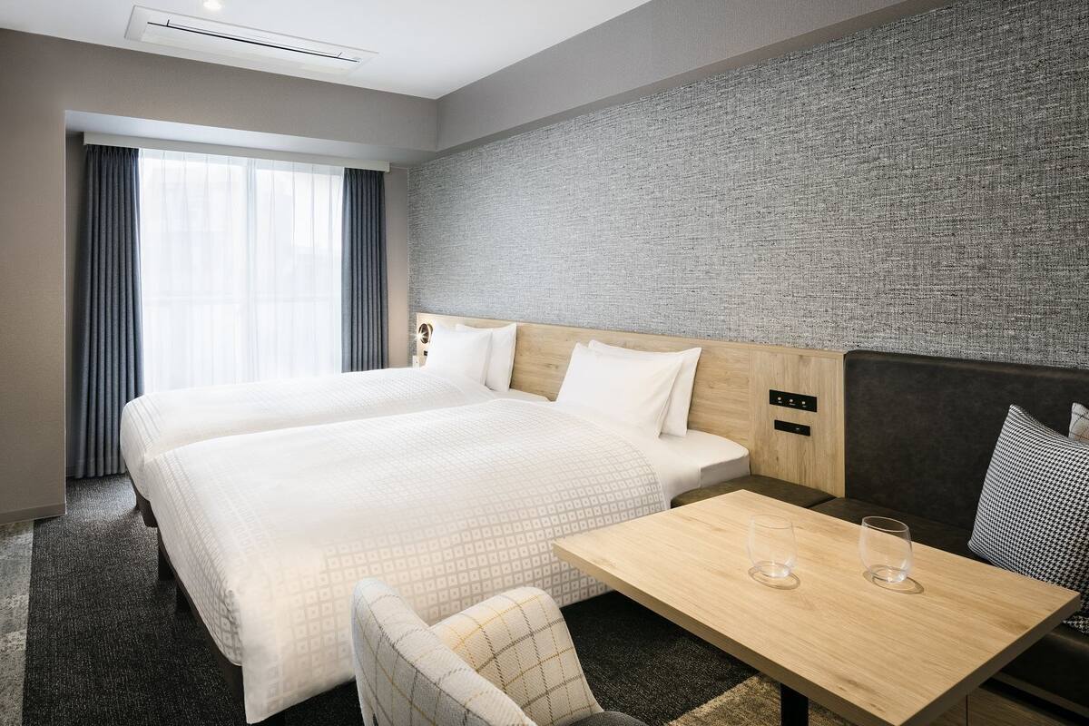 A hotel room with a large bed, a small table, a chair, and a TV.