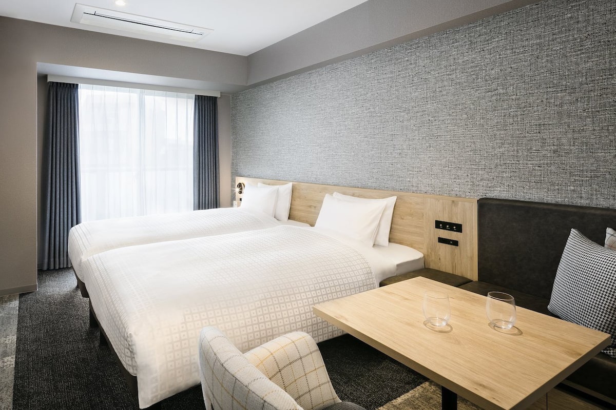 Une chambre d’hôtel avec un grand lit, une petite table, une chaise et un téléviseur.