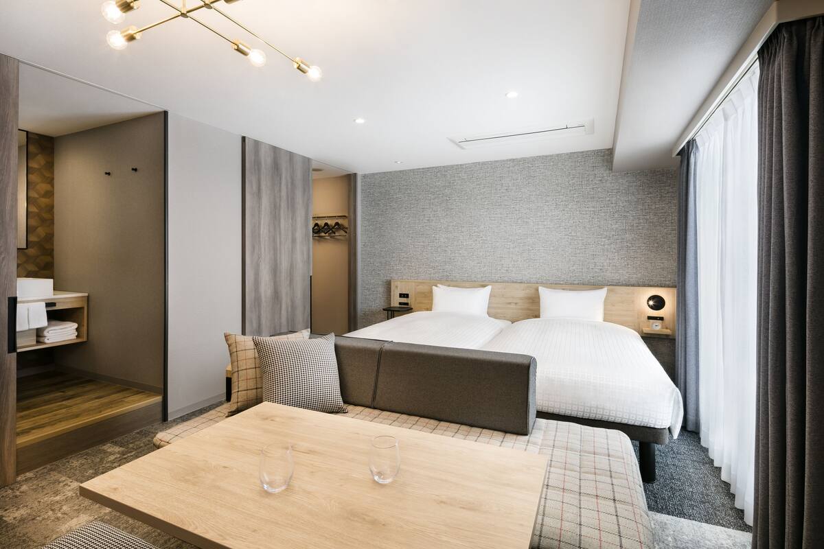 A modern hotel room with a large bed, a bedside table, a mirror, and a wardrobe.