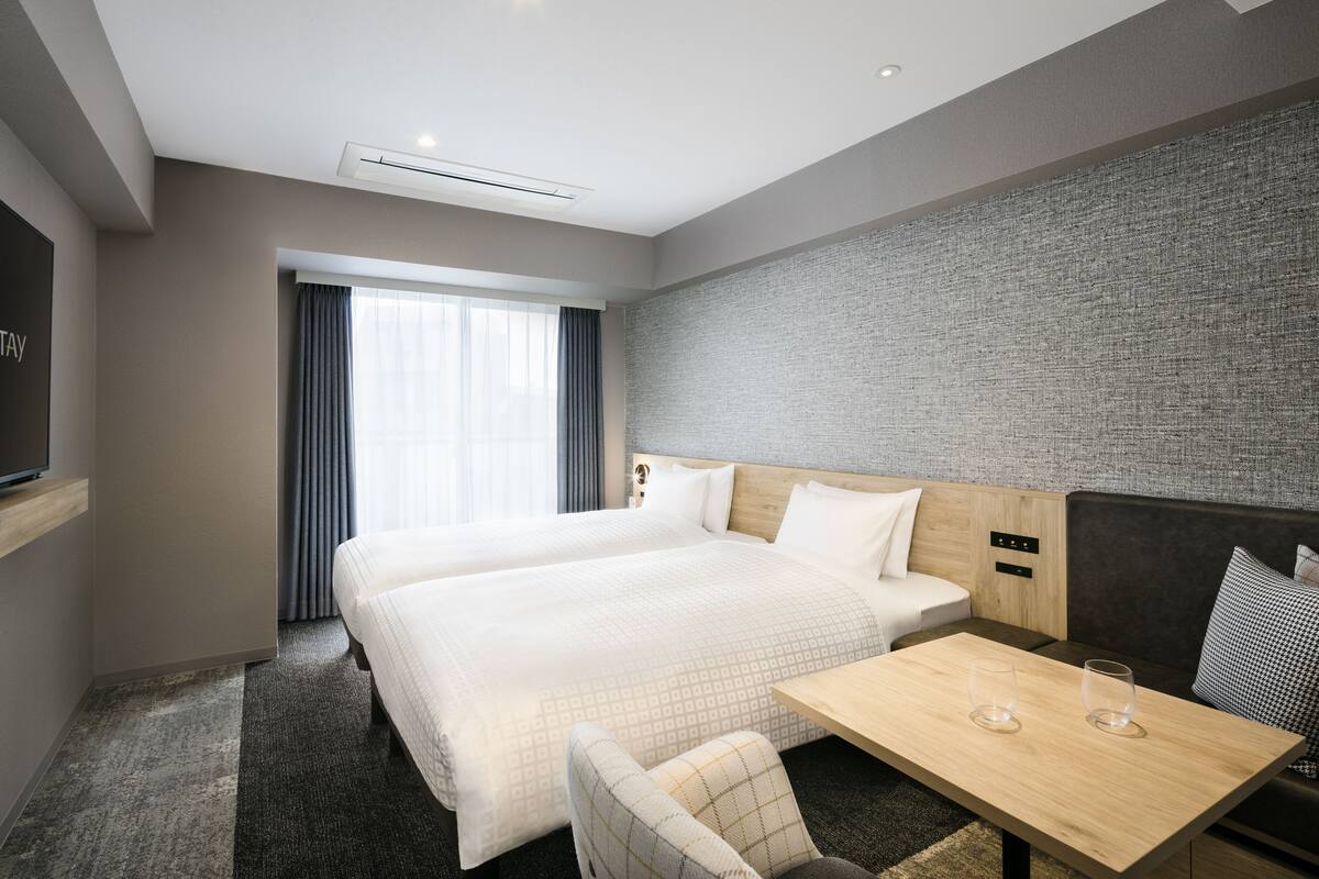 A hotel room with a large bed, a desk, a chair, and a television.