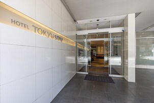 Una entrada de hotel moderna con puerta de vidrio y un letrero que dice HOTEL TOKYU STAY.