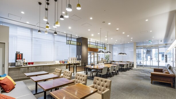 Un hall d’hôtel moderne doté d’un espace salon, de tables et d’un coin café.